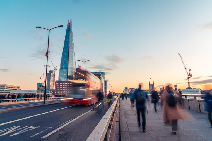 Tourists walking on London Bridge at sunset with the Shard and a red double-decker bus following the Employment Rights Act receiving Royal Assent